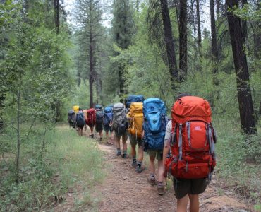 photo of *group of people backpacking summer camp day time*, taken from the back --ar 3:2 --v 7.0