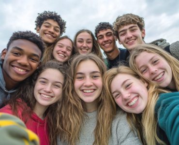 photo of a *group of diverse young adults* smiling and taking a selfie together outdoors on a cloudy day. The group has a casual, friendly atmosphere, with people of different backgrounds and styles. Some wear brightly colored casual clothing, while others are dressed in more neutral tones. The setting is urban, with the sky overcast, creating a relaxed and joyful vibe. Natural lighting, with the focus on their happy faces and the casual group pose. --ar 3:2